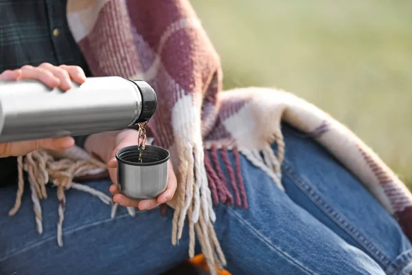 Woman drinking hot tea from thermos outdoors — Stock Photo, Image