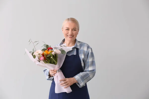 Female florist with bouquet on light background — Stock Photo, Image