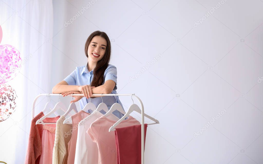 Young woman standing near clothes rack in dressing room