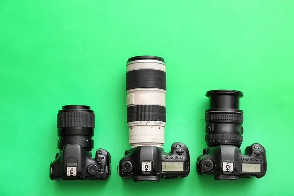Different professional photo cameras on color background — Stock Photo, Image