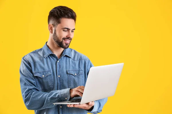 Männlicher Programmierer mit Laptop auf farbigem Hintergrund — Stockfoto