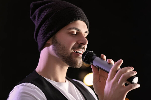 Красивый певец с микрофоном на сцене
