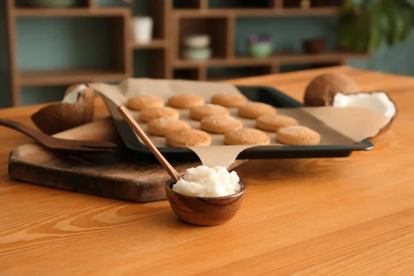 Кокосовое масло с вкусным печеньем на деревянном столе — стоковое фото