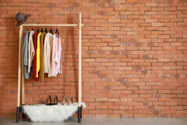 Gestell mit stylischer Kleidung in der Nähe der Ziegelwand — Stockfoto