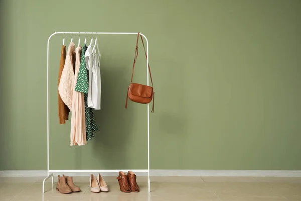 Cremalheira com roupas elegantes perto da parede de cor — Fotografia de Stock