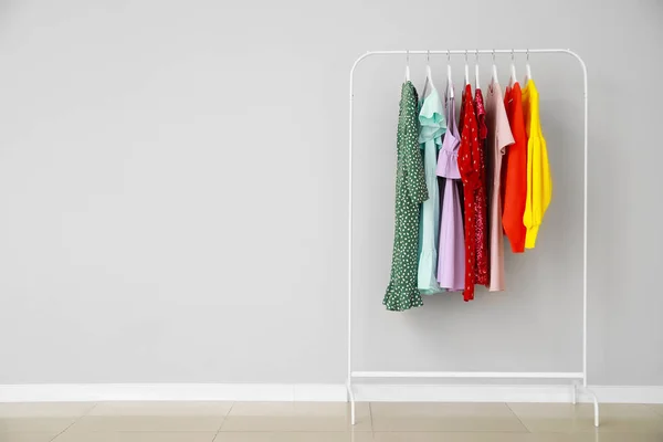 Bastidor con ropa elegante cerca de la pared gris — Foto de Stock