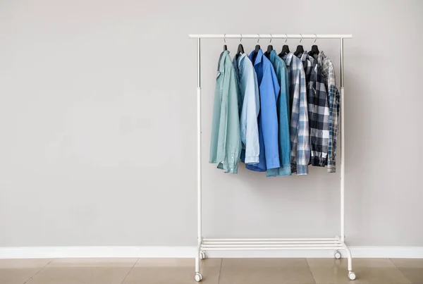 Bastidor con ropa elegante cerca de la pared gris — Foto de Stock