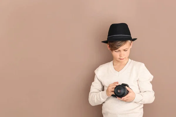 Schattige kleine fotograaf met professionele camera op kleur achtergrond — Stockfoto