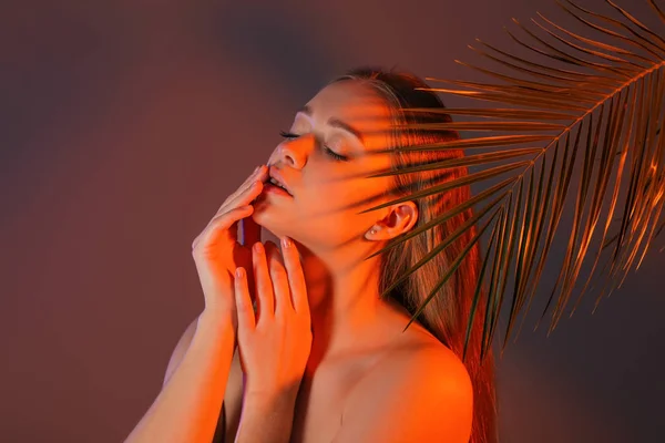 Retrato dentado de bela jovem com folha tropical sobre fundo de cor — Fotografia de Stock