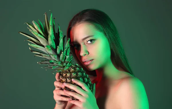 Tonas porträtt av vacker ung kvinna med välsmakande ananas på färg bakgrund — Stockfoto