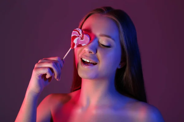 Tonas porträtt av vacker ung kvinna med läckra Lollipop på färg bakgrund — Stockfoto