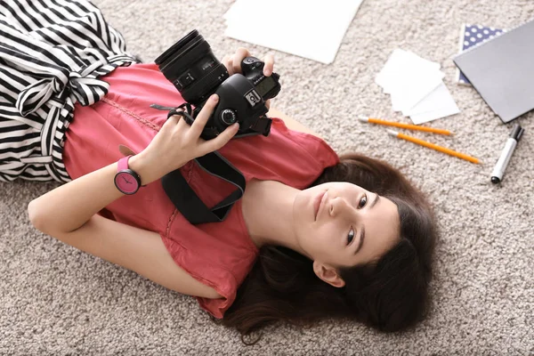 Mladá dívka s moderní fotoaparát ležící na podlaze doma — Stock fotografie