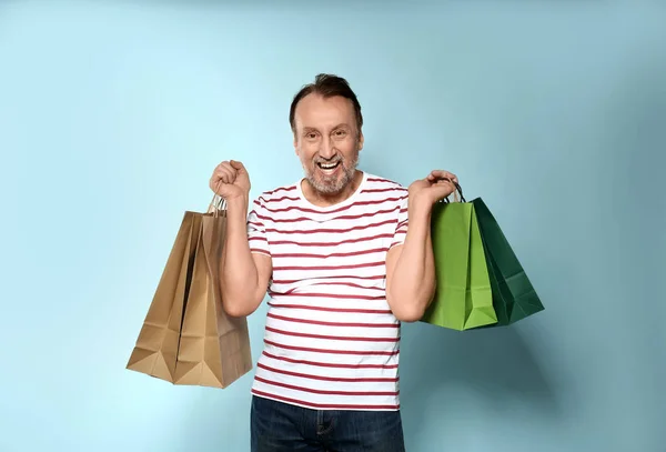 Portrét šťastného zralých s nákupními taškami na barevném pozadí — Stock fotografie