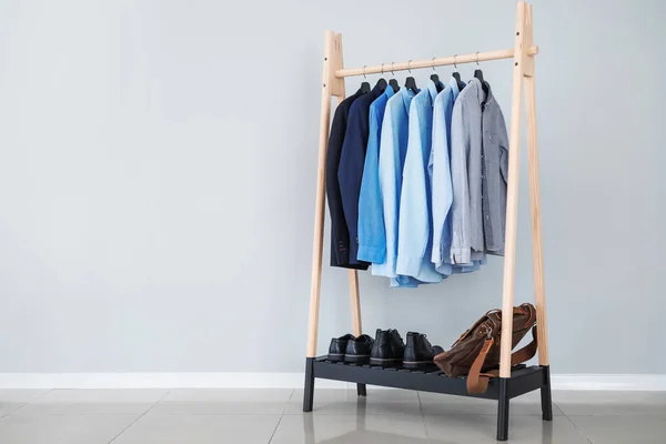 Rack with stylish male clothes near light wall — Stock Photo, Image