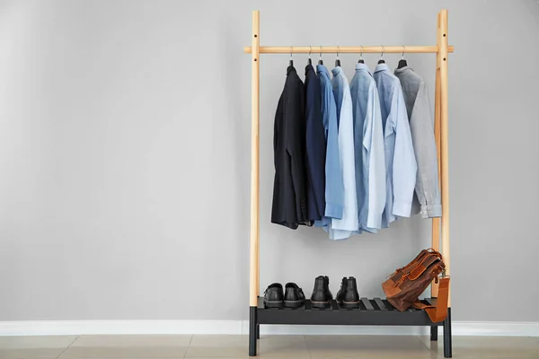 stock image Rack with stylish male clothes near light wall