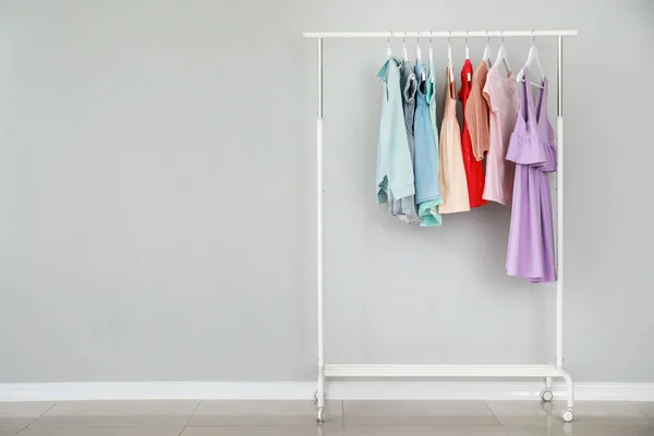 Bastidor con ropa para niños con estilo cerca de la pared de luz — Foto de Stock