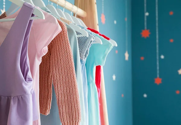 Rack with female clothes near color wall — Stock Photo, Image