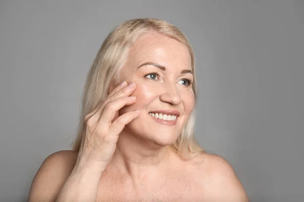 Mature woman with healthy skin on grey background — Stock Photo, Image