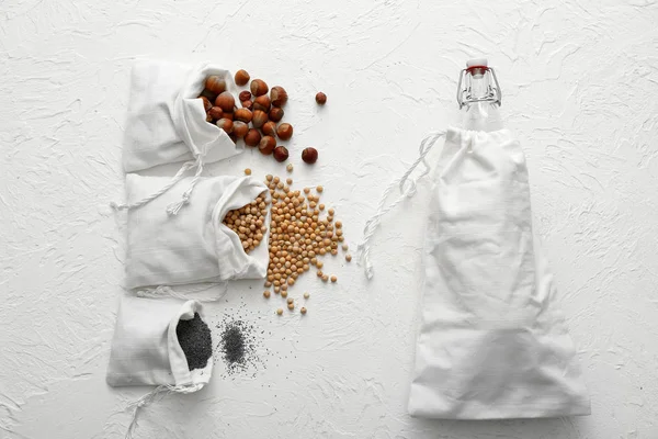 Cotton bags with fresh products and glass bottle on white background. Zero waste concept
