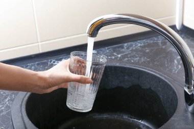 Kadın mutfak musluk su ile cam doldurma