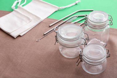 Cam kavanozlar, kumaş torbalar ve metal pipetler renkli arka plan üzerinde. Sıfır atık kavramı