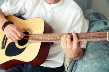 yakışıklı genç adam evde gitar çalıyor.