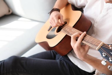 yakışıklı genç adam evde gitar çalıyor.