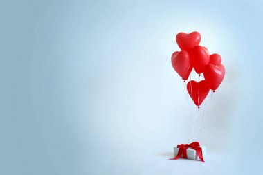 Hafif arka planda hediye kutusu ile kalp şeklinde hava balonları