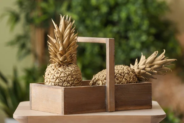 Holzkorb mit goldenen Ananas auf dem Tisch — Stockfoto