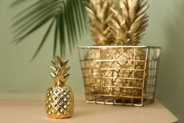 Košík se zlatými ananasy na stole proti zelenému pozadí — Stock fotografie