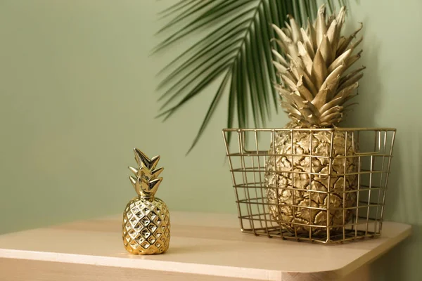 Basket with golden pineapples on table against green background — Stock Photo, Image