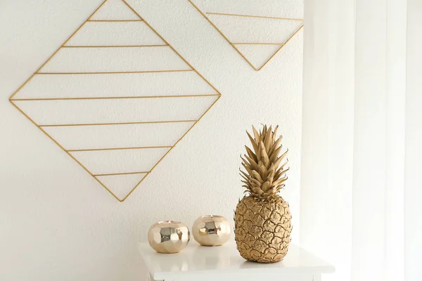 Piña dorada con velas en la mesa cerca de la pared blanca —  Fotos de Stock