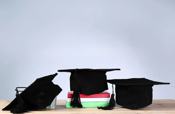Mortar boards and books on table. Concept of high school graduation — Stock Photo, Image