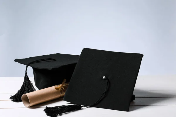 Mortar boards and diploma on table. Concept of high school graduation — Stock Photo, Image