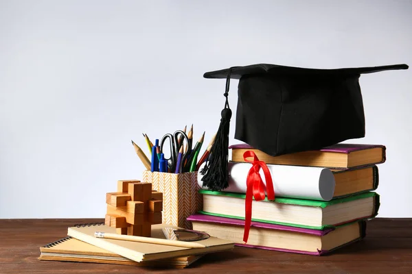 Mortar board, diploma, stationery and books on table. Concept of high school graduation — Stock Photo, Image
