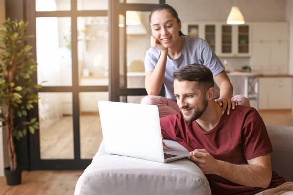 Lyckliga unga par med laptop hemma — Stockfoto