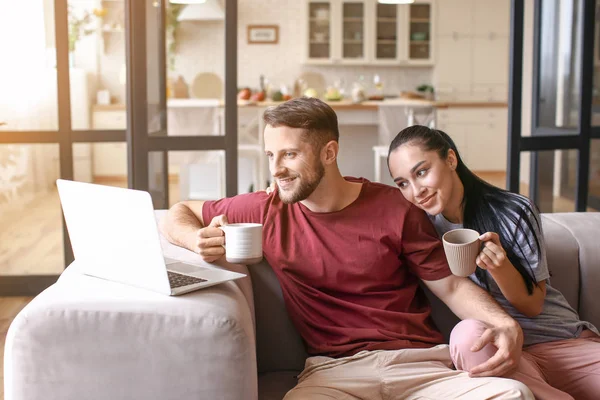 Feliz pareja joven con portátil bebiendo té en casa — Foto de Stock