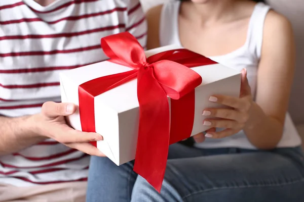 Happy young couple with gift at home, closeup — Stock Photo, Image