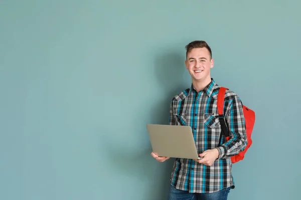 Хлопчик-підліток з ноутбуком на кольоровому фоні — стокове фото
