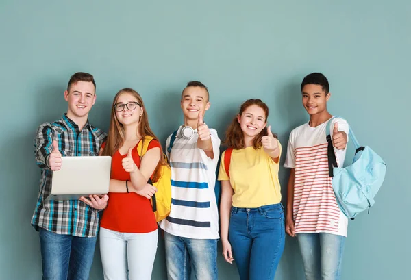 Tinédzserek csoportja mutatja hüvelykujját a színes háttér — Stock Fotó
