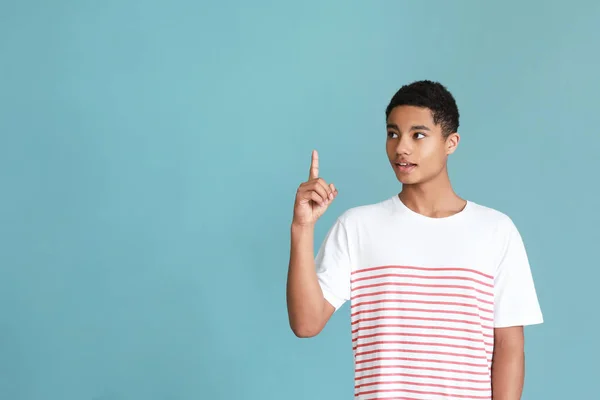 African-American teenage boy with raised index finger on color background — Stock Photo, Image