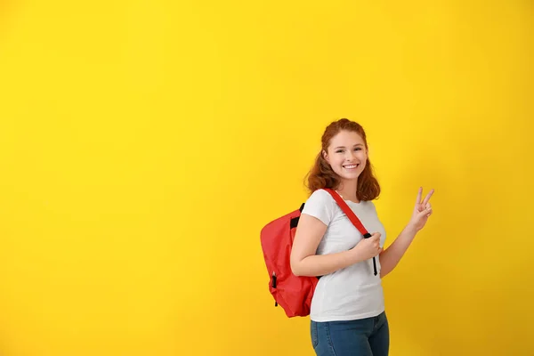 Söt tonårs flicka visar seger gest på färg bakgrund — Stockfoto
