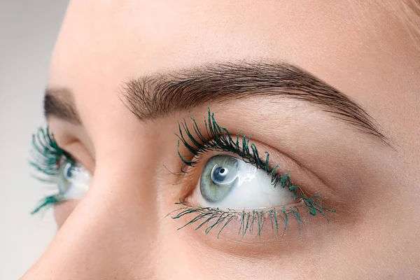 Bella giovane donna con mascara di colore applicato, primo piano — Foto Stock