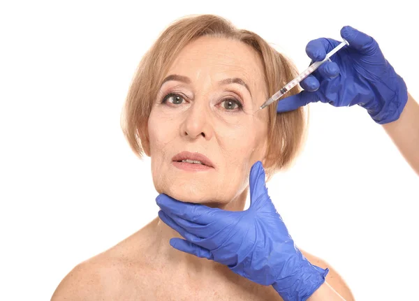 Beautiful mature woman receiving injection against white background — Stock Photo, Image