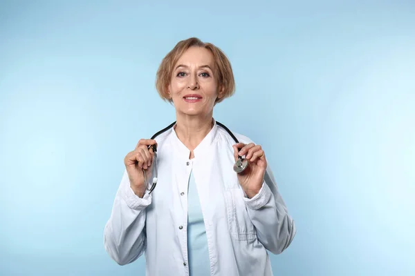 Mooie vrouwelijke arts op kleur achtergrond — Stockfoto