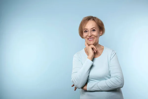 Mooie volwassen vrouw op kleur achtergrond — Stockfoto