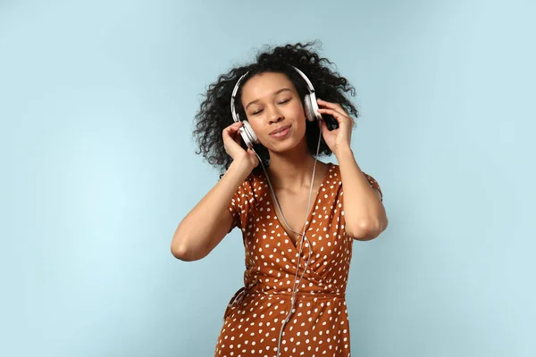 Young African-American woman listening to music on color background — Stock Photo, Image
