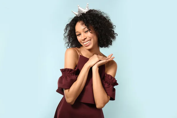 Happy African-American woman wearing crown on color background — Stock Photo, Image
