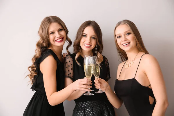 Piękne młode kobiety z kieliszków szampana na jasnym tle — Zdjęcie stockowe