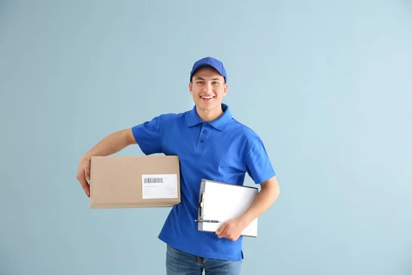 Delivery man med box och Urklipp på färg bakgrund — Stockfoto